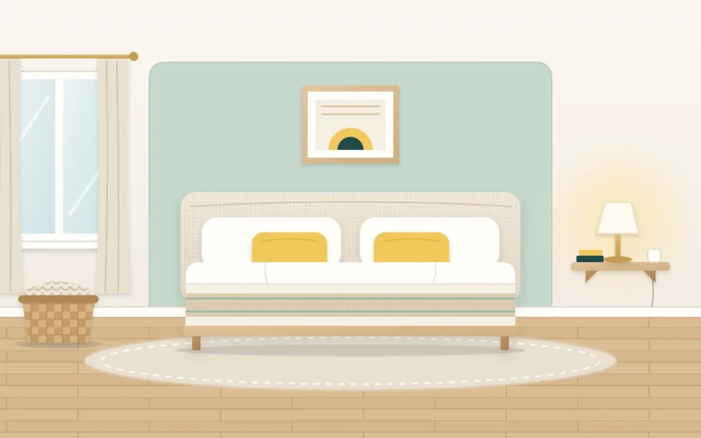 Compact bedroom with layered pale bedding and two accent pillows against a sage wall panel, a small wall shelf with a lamp and one framed print above the bed